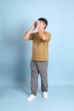 Mavi arka planda sıradan giyinmiş kıdemli Asyalı adam..