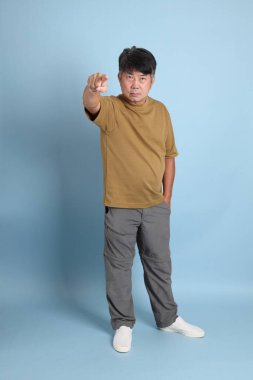 Mavi arka planda sıradan giyinmiş kıdemli Asyalı adam..