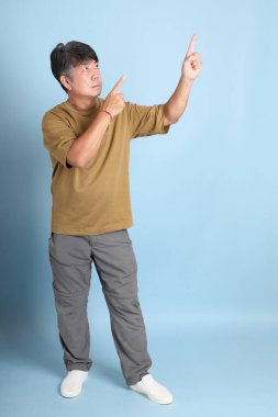 Mavi arka planda sıradan giyinmiş kıdemli Asyalı adam..