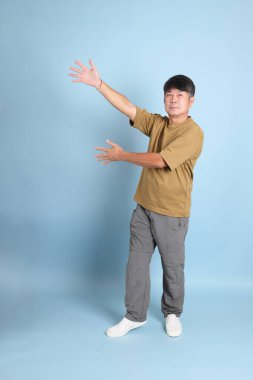 Mavi arka planda sıradan giyinmiş kıdemli Asyalı adam..