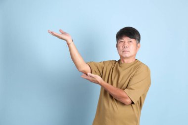 Mavi arka planda sıradan giyinmiş kıdemli Asyalı adam..