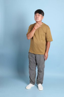 Mavi arka planda sıradan giyinmiş kıdemli Asyalı adam..