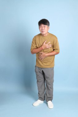 Mavi arka planda sıradan giyinmiş kıdemli Asyalı adam..
