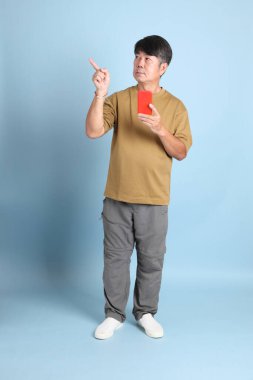 Mavi arka planda sıradan giyinmiş kıdemli Asyalı adam..