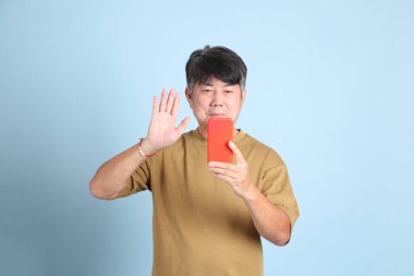 Mavi arka planda sıradan giyinmiş kıdemli Asyalı adam..