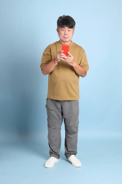 Mavi arka planda sıradan giyinmiş kıdemli Asyalı adam..