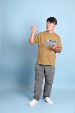 Mavi arka planda sıradan giyinmiş kıdemli Asyalı adam..