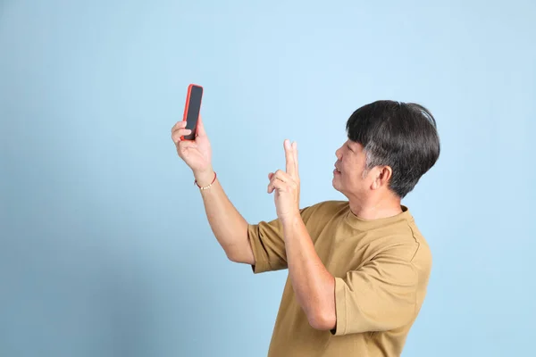 Der Ältere Asiatische Mann Mit Lässiger Kleidung Steht Auf Blauem — Stockfoto