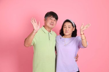 Pembe arka planda sıradan kıyafetler giyen son sınıf Asyalı çift..