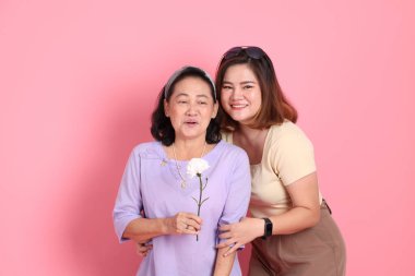 Pembe arka planda sıradan giyinmiş Asyalı aile..