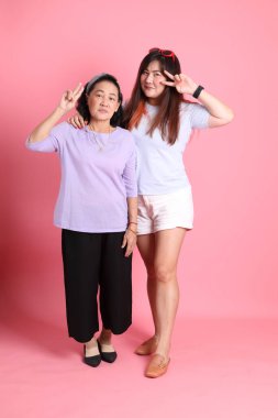 Pembe arka planda sıradan giyinmiş Asyalı aile..