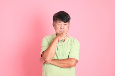 Pembe arka planda sıradan giyinmiş kıdemli Asyalı adam..