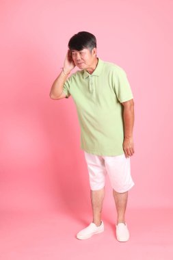 Pembe arka planda sıradan giyinmiş kıdemli Asyalı adam..