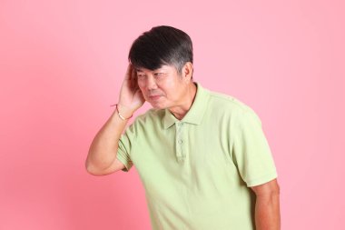 Pembe arka planda sıradan giyinmiş kıdemli Asyalı adam..