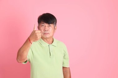 Pembe arka planda sıradan giyinmiş kıdemli Asyalı adam..