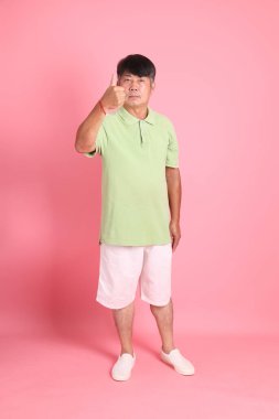 Pembe arka planda sıradan giyinmiş kıdemli Asyalı adam..