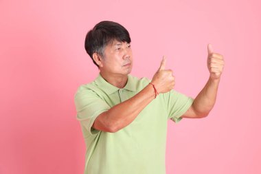 Pembe arka planda sıradan giyinmiş kıdemli Asyalı adam..