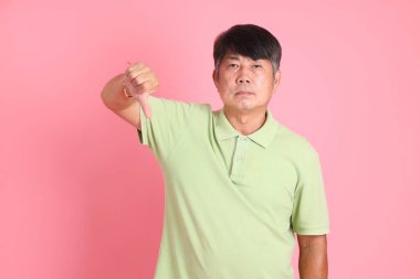 Pembe arka planda sıradan giyinmiş kıdemli Asyalı adam..