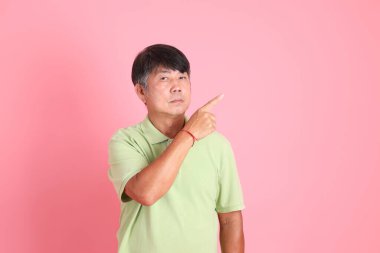 Pembe arka planda sıradan giyinmiş kıdemli Asyalı adam..