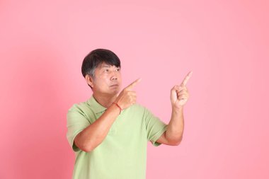 Pembe arka planda sıradan giyinmiş kıdemli Asyalı adam..