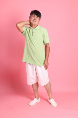 Pembe arka planda sıradan giyinmiş kıdemli Asyalı adam..