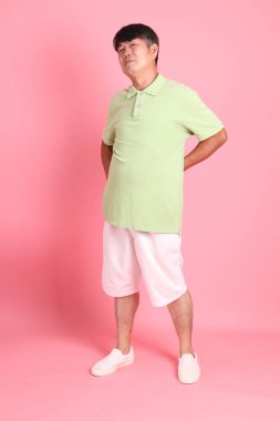 Pembe arka planda sıradan giyinmiş kıdemli Asyalı adam..