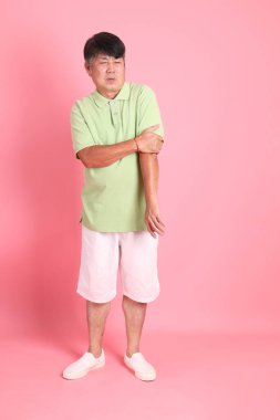 Pembe arka planda sıradan giyinmiş kıdemli Asyalı adam..