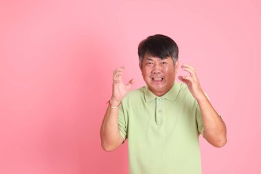 Pembe arka planda sıradan giyinmiş kıdemli Asyalı adam..