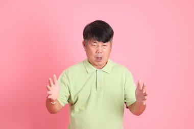 Pembe arka planda sıradan giyinmiş kıdemli Asyalı adam..