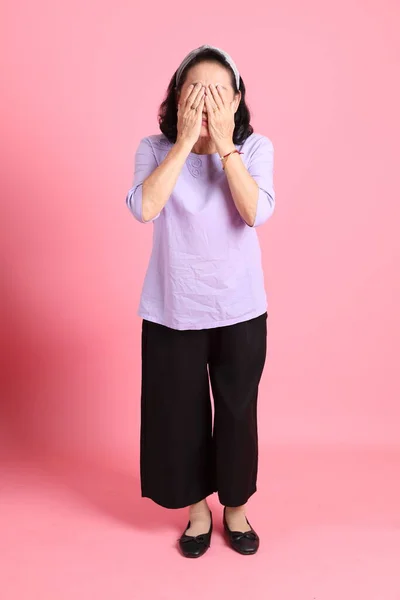 Pembe Arka Planda Kahverengi Giyinmiş Yaşlı Asyalı Kadın — Stok fotoğraf