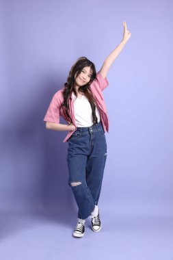 Mor arka planda dikilen sıradan giysili tatlı Asyalı kız..