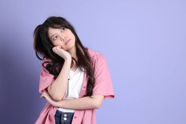 Mor arka planda dikilen sıradan giysili tatlı Asyalı kız..