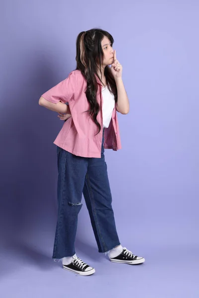 那个穿着休闲装站在紫色背景上的可爱的年轻亚洲女孩 — 图库照片