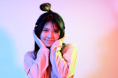 Stüdyoda jel rengi yıldırımın altında poz veren sıradan giyinmiş genç Asyalı kız..