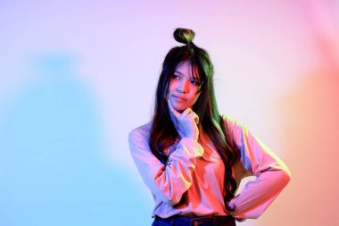 Stüdyoda jel rengi yıldırımın altında poz veren sıradan giyinmiş genç Asyalı kız..