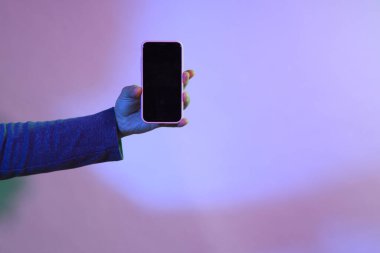 Asyalı adam canlı rengin altında akıllı telefonu tutuyor..