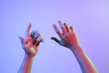 Asyalı adamın elleri parlak renkli ışıkların altında.