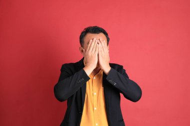 Kırmızı arka planda duran Asyalı orta yaşlı adam..