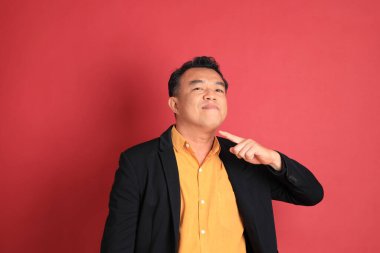 Kırmızı arka planda duran Asyalı orta yaşlı adam..