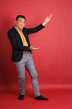 Kırmızı arka planda duran Asyalı orta yaşlı adam..