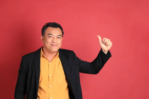 The Asian middle aged man standing on the red background.