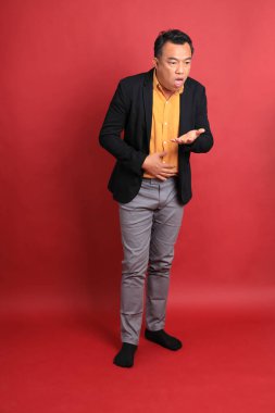 Kırmızı arka planda duran Asyalı orta yaşlı adam..