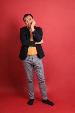 Kırmızı arka planda duran Asyalı orta yaşlı adam..