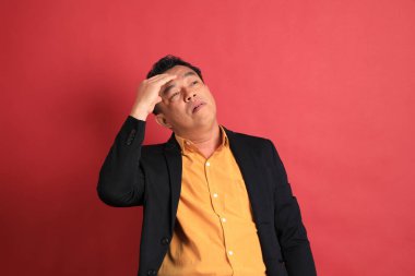 Kırmızı arka planda duran Asyalı orta yaşlı adam..