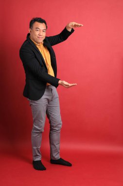 Kırmızı arka planda duran Asyalı orta yaşlı adam..