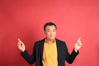 Kırmızı arka planda duran Asyalı orta yaşlı adam..