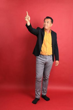 Kırmızı arka planda duran Asyalı orta yaşlı adam..