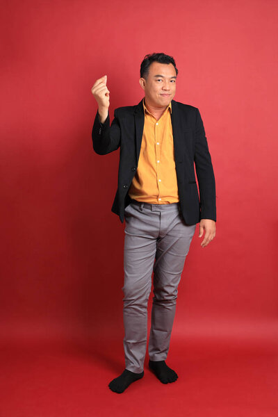 The Asian middle aged man standing on the red background.