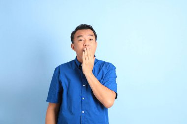 Mavi arka planda duran Asyalı orta yaşlı adam..