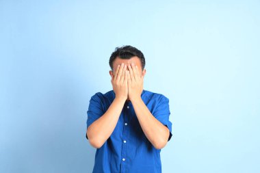 Mavi arka planda duran Asyalı orta yaşlı adam..